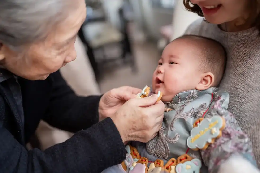 收涎儀式細節拍攝 - 長輩拿餅乾在寶寶嘴邊抹動並說祝福語的溫馨瞬間