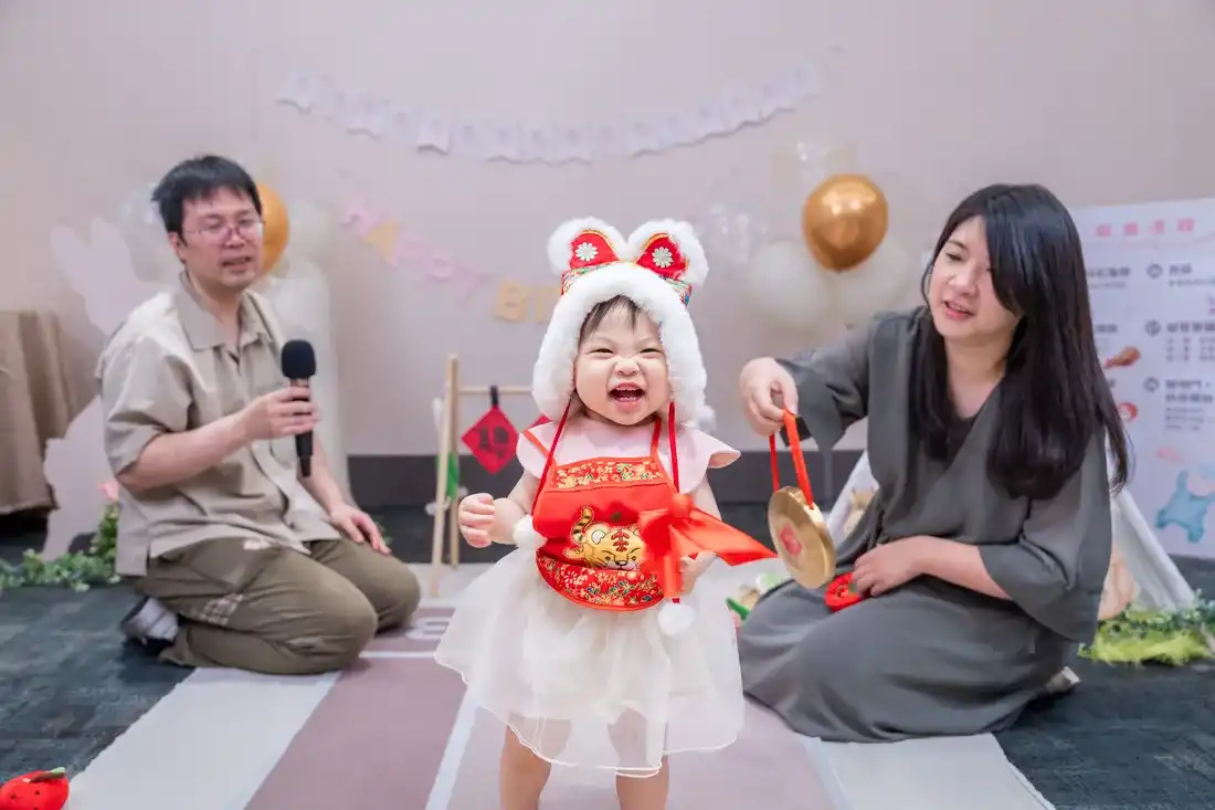 台北凱撒飯店，抓周活動側拍 - 父母在旁引導寶寶爬行與拍手鼓勵的自然互動畫面
