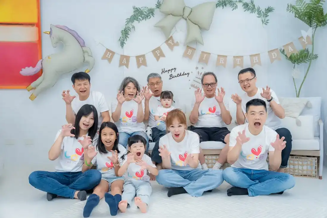 家族慶生派對攝影 - 大家族在生日佈置前擺出俏皮動作的歡樂大合照